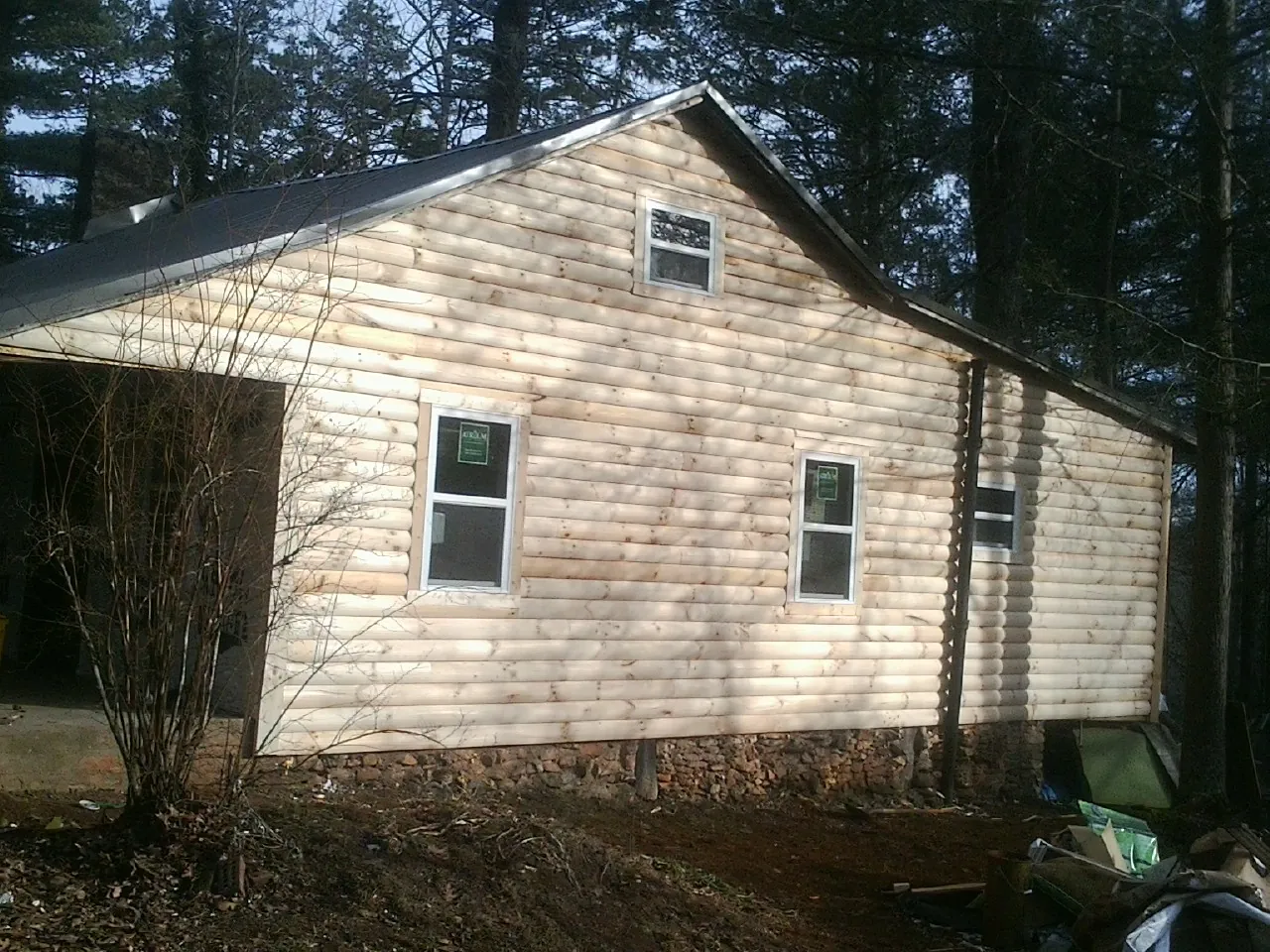 New log siding and dark metal roofing on a gable end in Howe