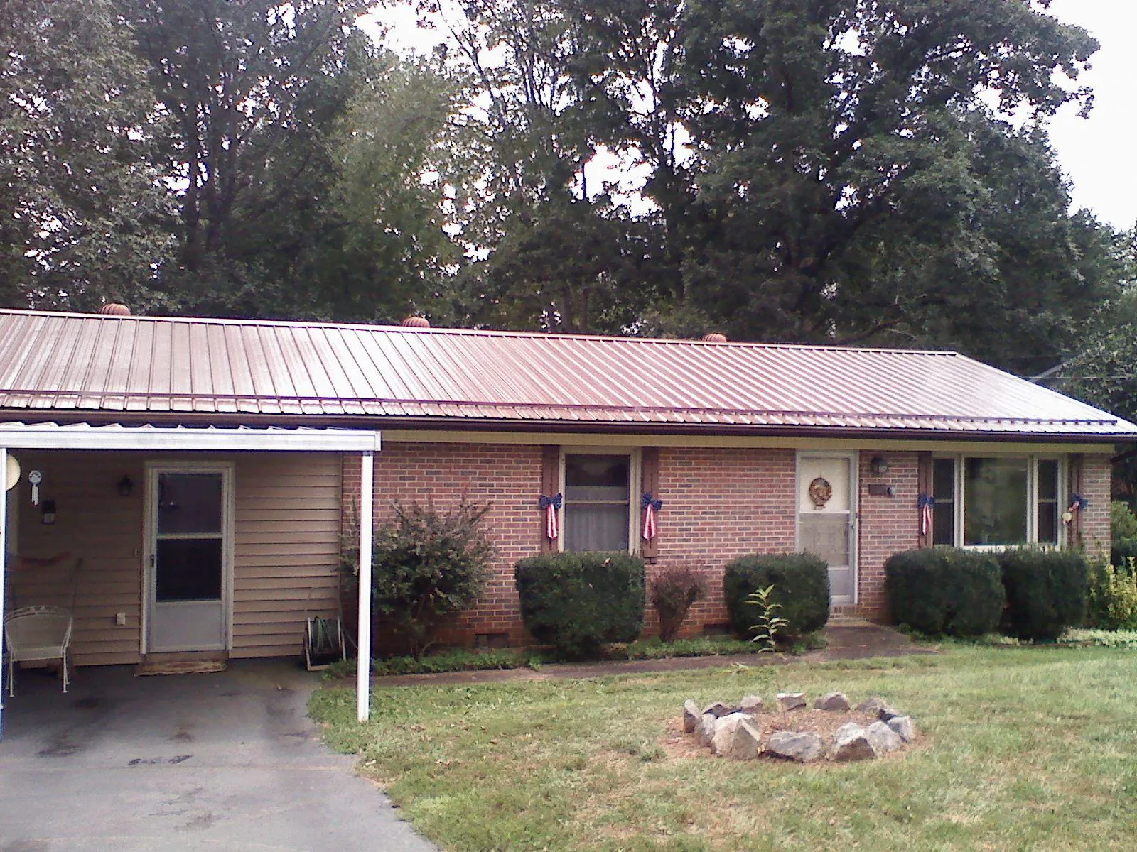 Bronze metal roof and carport on a brick ranch home — Roof Repair work by our crew in Howe